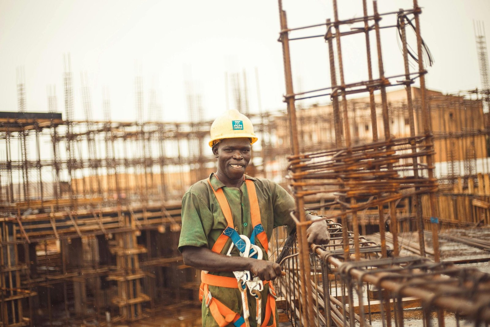 Smiling construction worker wearing a helmet at a site in Kitgum Matidi, Uganda.